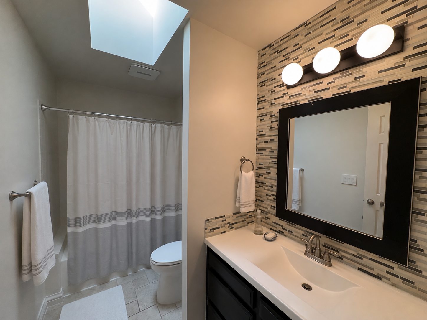 Full bathroom with skylight and tiled vanity wall at Casa Rita, Bentonville AR