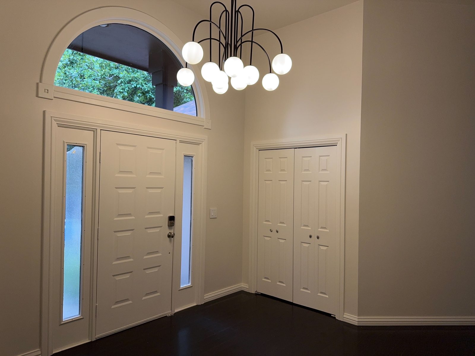 Entry foyer with arched transom window and globe chandelier at Casa Rita, Bentonville AR